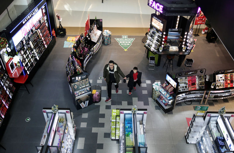 © Reuters. A man and a boy walk at a shopping center in Beijing