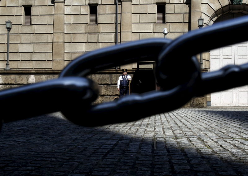 © Reuters. A security officer is seen through a chain link as he stands guard outside the Bank of Japan headquarters in Tokyo