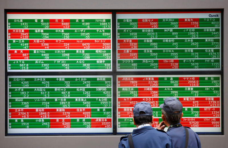 © Reuters. Men look at stock prices before brokerage in Tokyo