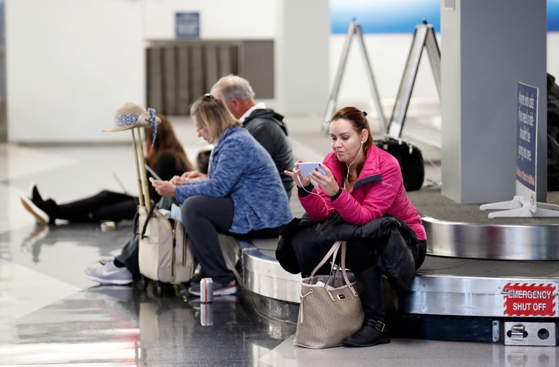 © Reuters. Passageiros esperam em uma esteira de bagagens no aeroporto de Chicago após uma nevasca provocar o cancelamento de centenas de voos