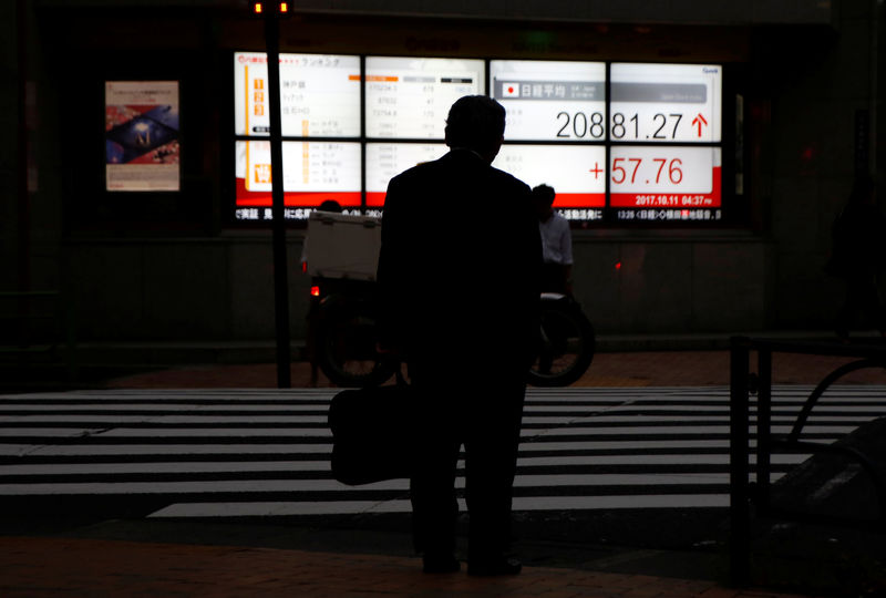 © Reuters. A man stands in front of an electronic board showing Japan's Nikkei average outside a brokerage in Tokyo