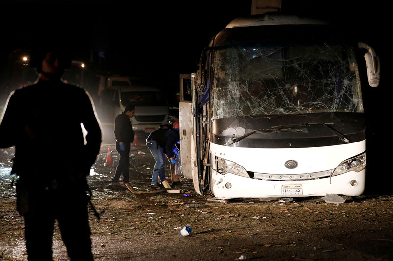 © Reuters. Policías observan los restos de un autobús tras sufrir una explosión en Giza. Egipto