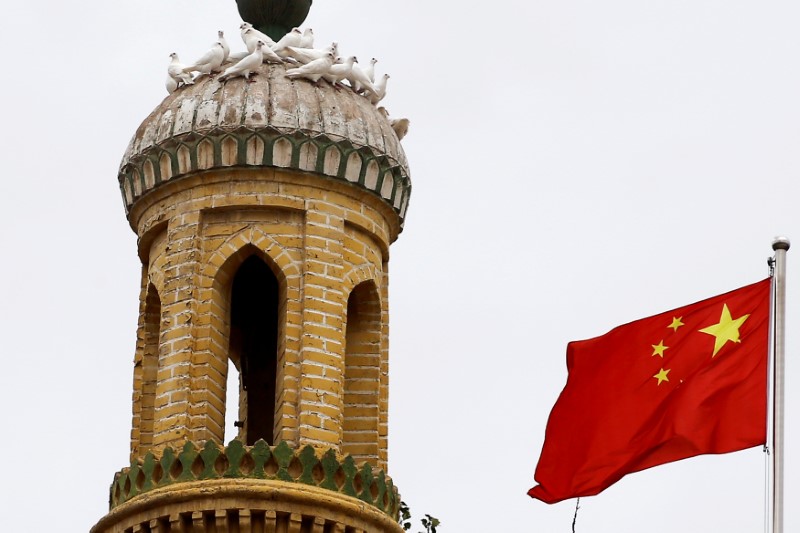 © Reuters. A Chinese national flag flutters near a minaret of the ancient Id Kah Mosque in the Old City in Kashgar