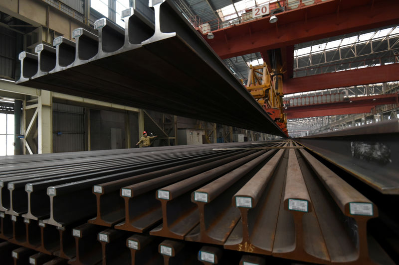 © Reuters. FILE PHOTO: A worker directs a crane lifting steel rails at a steel factory in Handan