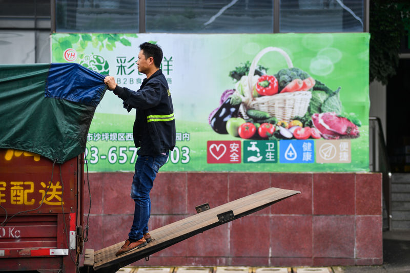 © Reuters. Worker adjusts a cover on the back of a truck outside a warehouse of Yonghui Superstores in Chongqing