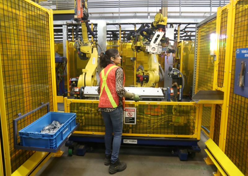 © Reuters. FILE PHOTO: Worker loads part for welding in robot bay at Alfield Industries, a subsidiary of Martinrea, one of three global auto parts makers in Canada.