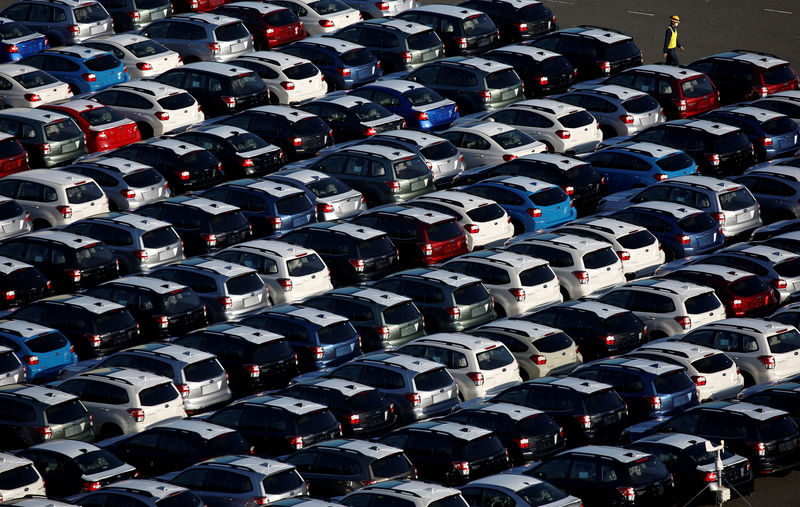 © Reuters. FILE PHOTO - A worker walks past newly produced cars at an industrial port in Kawasaki