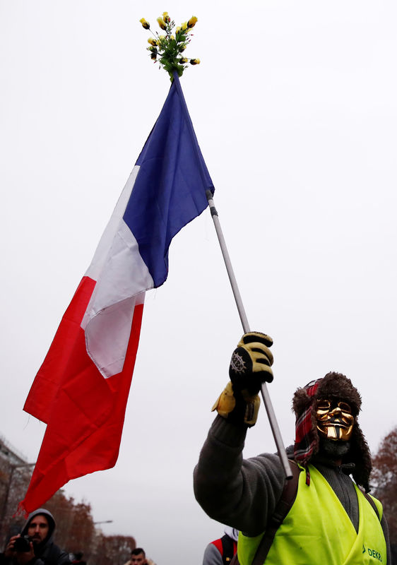 © Reuters. A protester holding a French flag takes part in a demonstration by the "yellow vests" movement on the Champs Elysees near the Arc de Triomphe in Paris