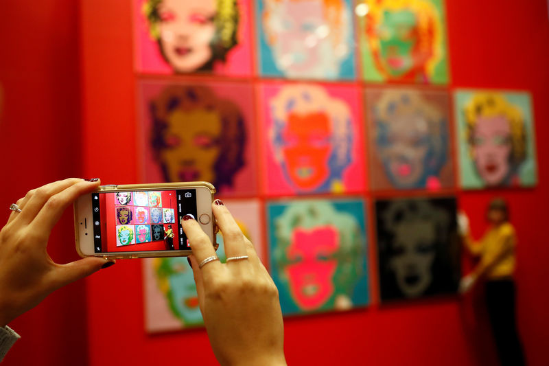 © Reuters. Mulher tira foto com celular de telas de Marilyn Monroe em exposição de Andy Warhol em Londres