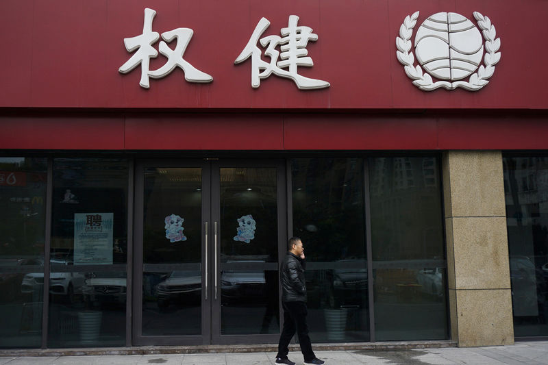 © Reuters. Man walks outside a branch of traditional Chinese medicine (TCM) firm Quanjian Group, in Hangzhou