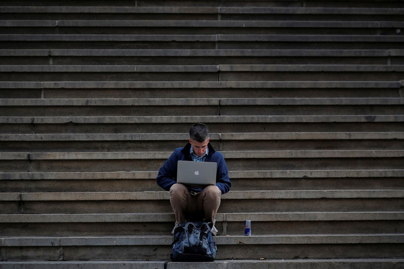 © Reuters. A man uses his Apple laptop on the steps of Federal Hall on Wall St. in the financial district of New York