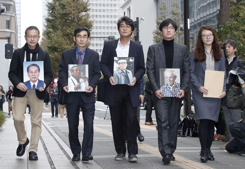© Reuters. Lawyers and activists hold photos of South Korean plaintiffs who were forced to work for a Japanese firm during World War Two as they visit Nippon Steel & Sumitomo Metal Corp's headquarters building in Tokyo