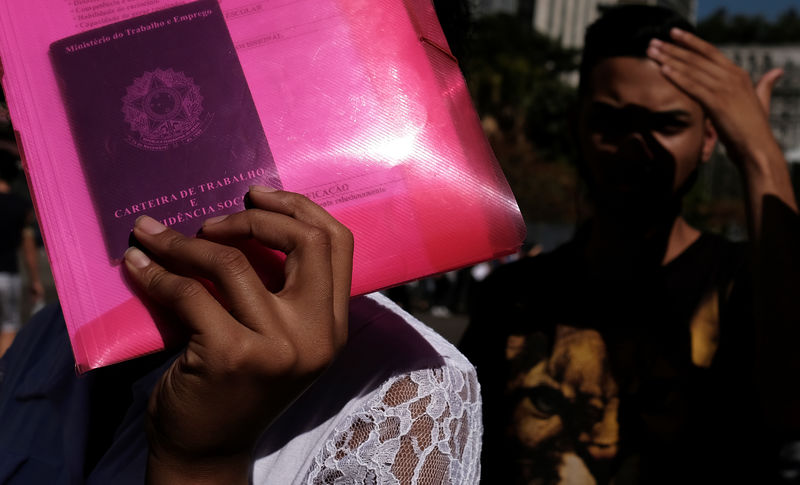 © Reuters. Mulher desempregada segura carteira de trabalho em fila de inscrições para vaga de emprego em São Paulo