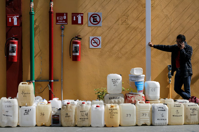 © Reuters. A man talks on a mobile phone while standing next to empty containers lined up at a gas station in Morelia