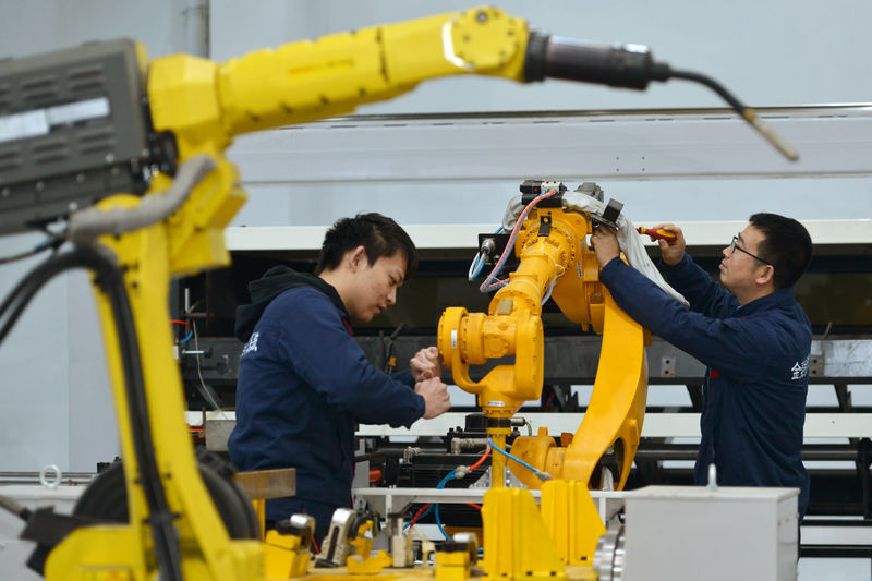 © Reuters. Men work on a production line manufacturing robotic arms at a factory in Huzhou, Zhejiang