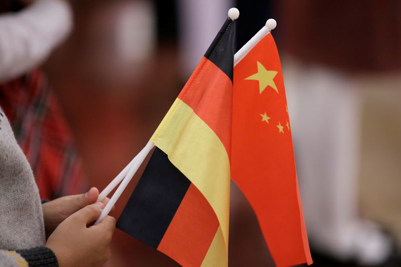 © Reuters. A student holds flags of China and Germany before a welcome ceremony in Beijing