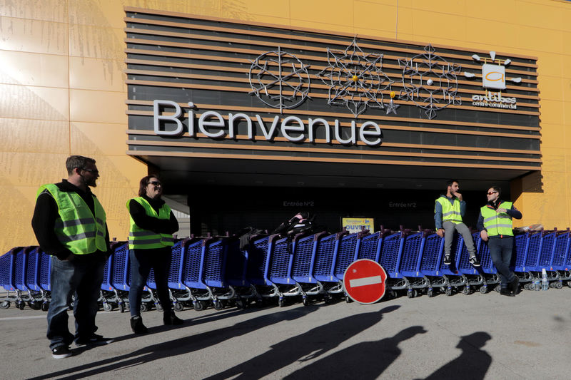© Reuters. FILE PHOTO: Protesters wearing yellow vests stand in front of a closed Carrefour supermarket as they take part in a demonstration of the "yellow vests" movement in Antibes
