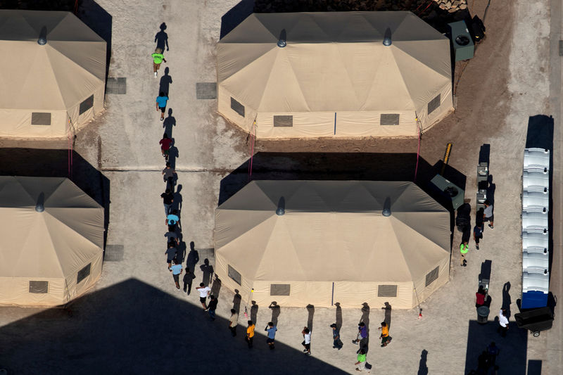 © Reuters. FILE PHOTO: Immigrant children are led by staff in single file between tents at a detention facility in Tornillo, Texas