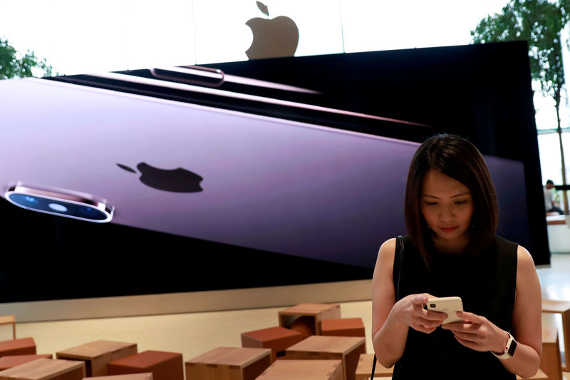 © Reuters. FILE PHOTO:  Woman checks her phone at a flagship Apple store at Iconsiam shopping mall in Bangkok
