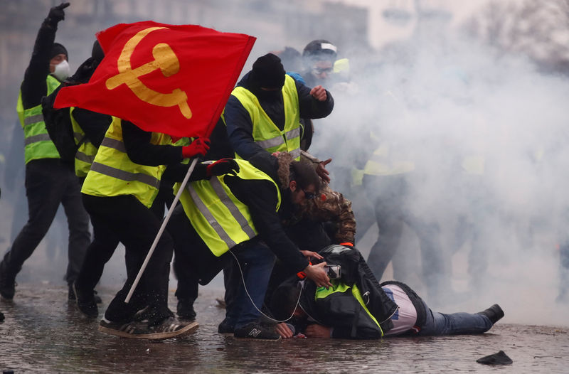 © Reuters. Chalecos amarillos ayuda a un herido durante una de las protestas junto al Arco del Triunfo en París.