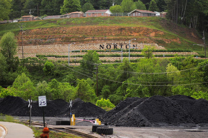 © Reuters. Homes built on a former surface strip coal mine sit above piles of coal in Norton