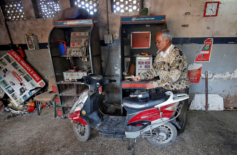 © Reuters. FILE PHOTO: A worker checks the power supply to recharge an electric scooter inside a workshop in Ahmedabad
