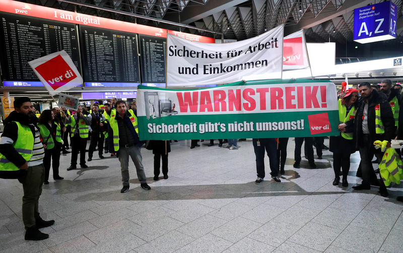 © Reuters. Union members hold banners during a strike over higher wages at Germany's largest airport in Frankfurt