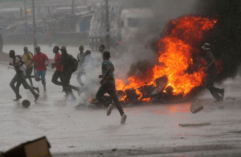 © Reuters. Pessoas correm ao lado de barricada em Harare