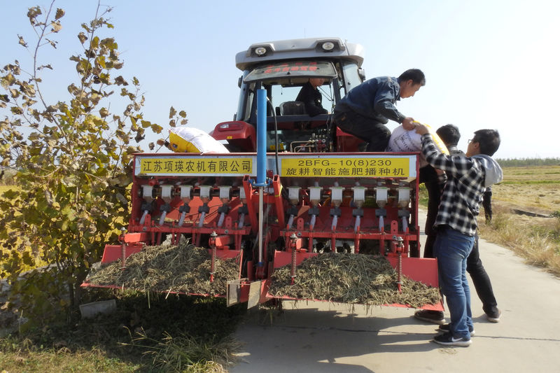 © Reuters. Staff members taking part in the experiment on automated farming machinery load fertilizer onto an automated tractor near a field in Xinghua