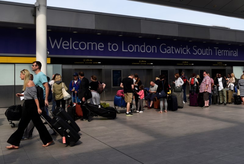 © Reuters. FILE PHOTO: People queue to enter the terminal at Gatwick Airport in southern England