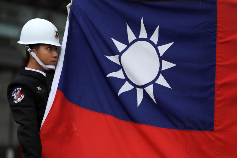 © Reuters. FILE PHOTO:  A military honour guard holds a Taiwanese national flag as he attending flag-raising ceremony at Chiang Kai-shek Memorial Hall, in Taipei