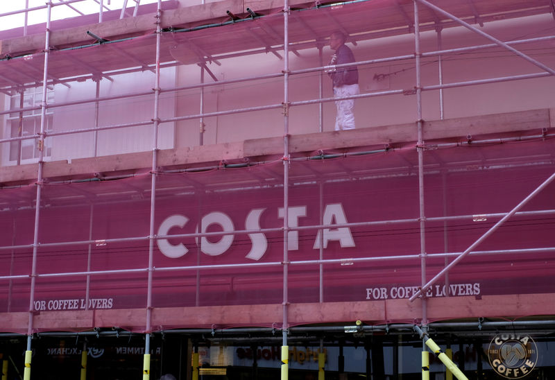© Reuters. FILE PHOTO: A worker walks above a Costa Coffee under going maintenance work in Loughborough