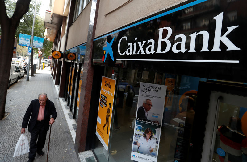 © Reuters. FILE PHOTO: A man walks past a Caixa bank branch in Barcelona