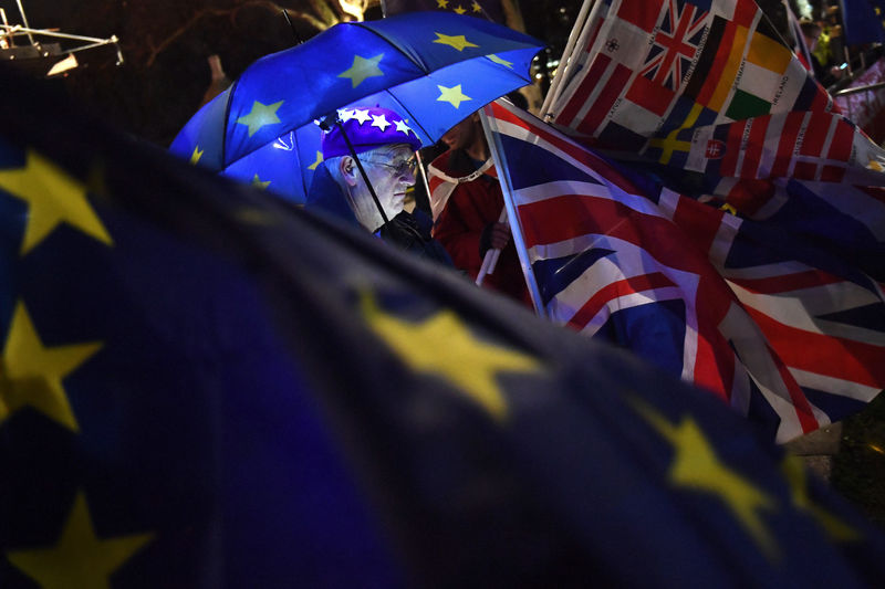 © Reuters. An anti-Brexit protester stands with an illuminated EU umbrella surrounded in flags outside the Houses of Parliament in London
