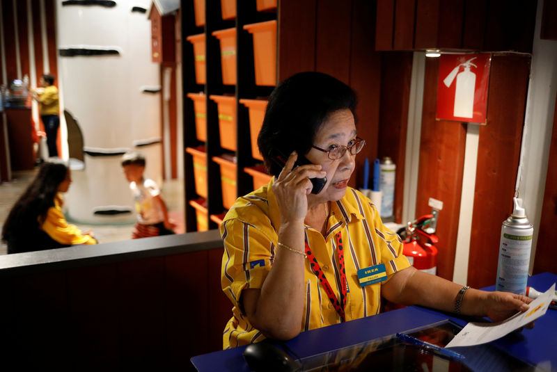 © Reuters. Soliano Paulina, 75, makes a call at the counter at Smaland, a play area for children at Ikea, in Singapore