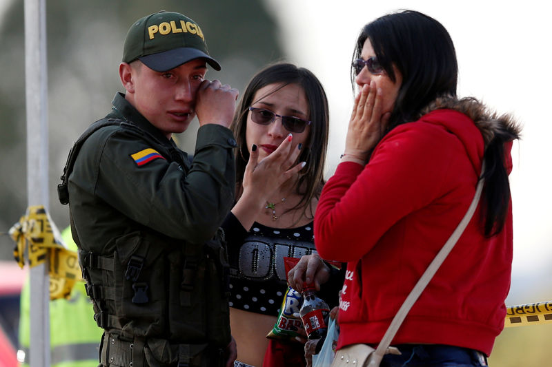 © Reuters. Policial e duas mulheres choram perto do local de explosão de carro-bomba, de acordo com autoridades, em Bogotá