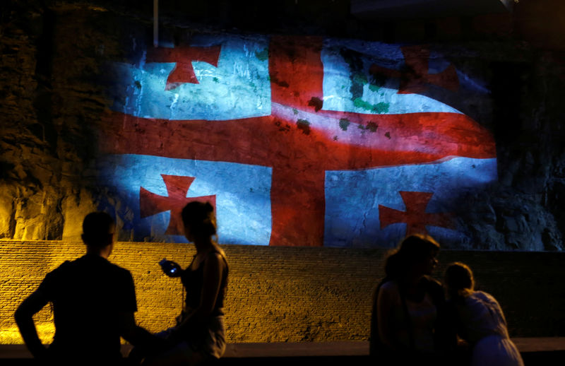 © Reuters. People watch a projection depicting Georgian flag on the wall at the historical part of Tbilisi