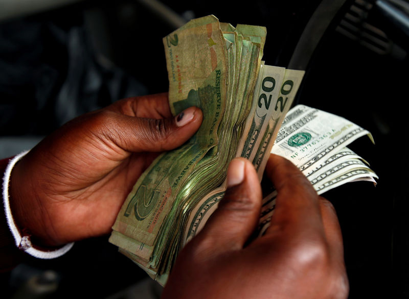 © Reuters. An illegal money changer counts dollar notes in Harare