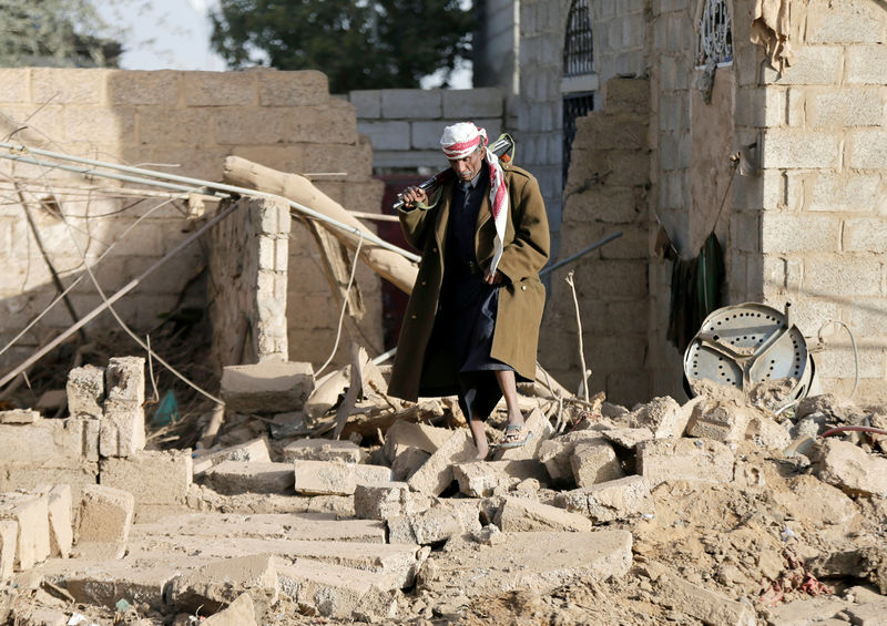 © Reuters. Man walks at the site of a Saudi-led air strike in Sanaa