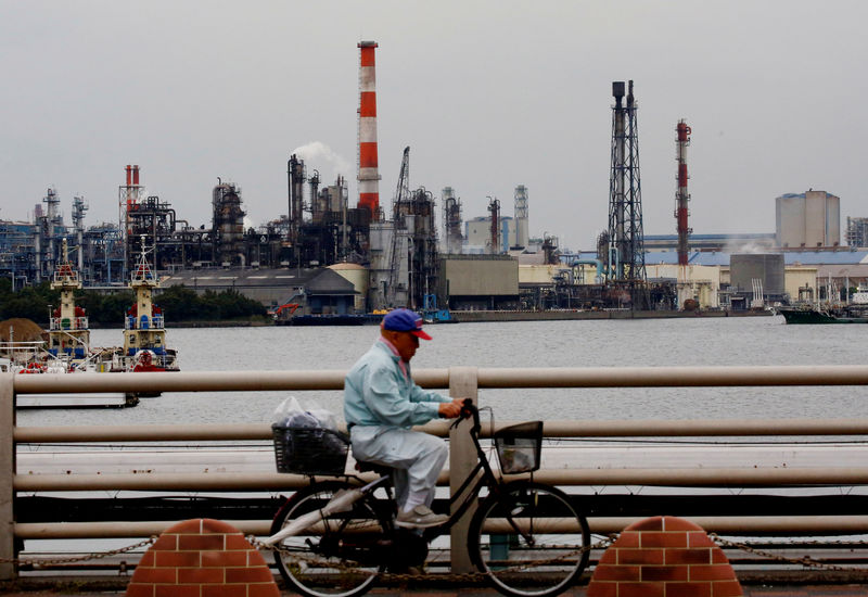 © Reuters. A man cycles past chimneys of facotries at the Keihin Industrial Zone in Kawasaki