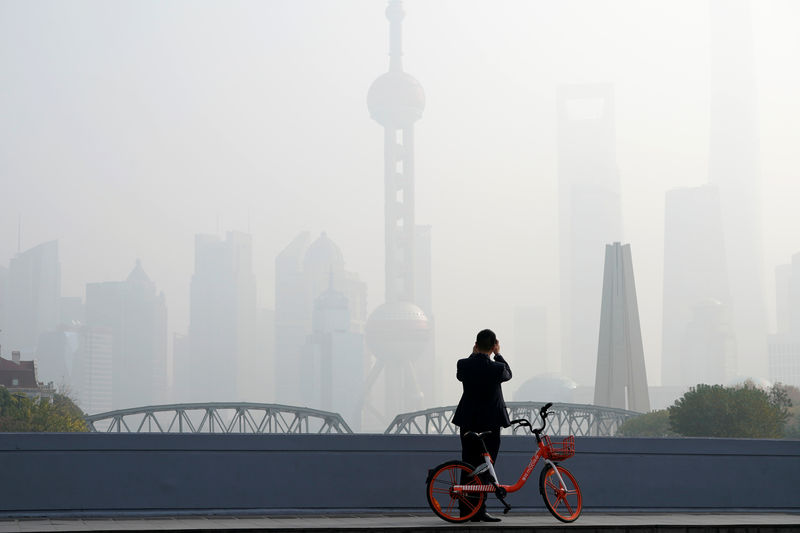 © Reuters. A man takes picture on a bridge in front of the financial district of Pudong covered in smog during a polluted day in Shanghai