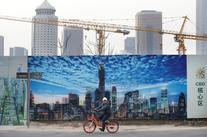 © Reuters. A man cycles outside the construction sites in Beijing's central business area