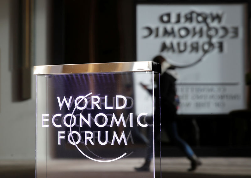 © Reuters. A person passes by a World Economic Forum logo in Davos
