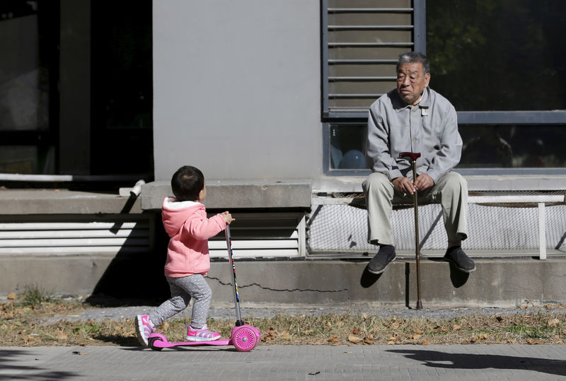 © Reuters. FILE PHOTO: An 80-year-old man, surnamed Li, watches as a girl plays at a residential community in Beijing