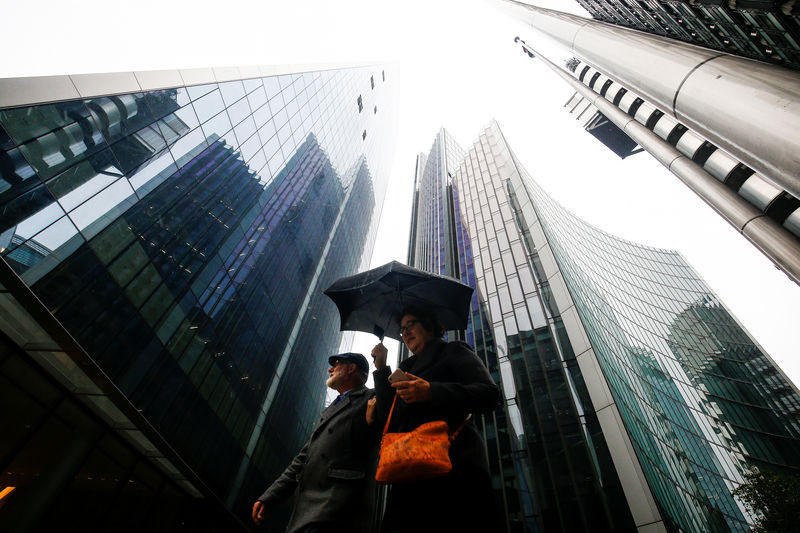 © Reuters. FILE PHOTO: People walk through the financial district during rainy weather in London