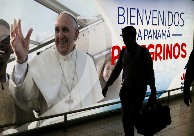 © Reuters. Passageiro passa por pôster com a foto do Papa Francisco no aeroporto de Tocumen, no Panamá