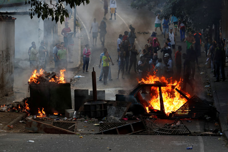 © Reuters. Demonstrators stand behind a burning barricade during a protest close to a National Guard outpost in Caracas