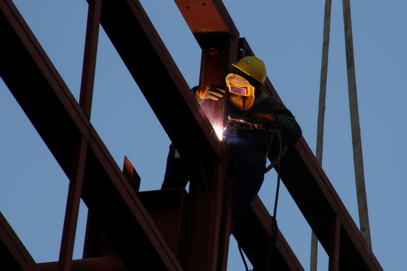 © Reuters. A worker welds as he stands on the metal frame of a building at a construction site in Beijing