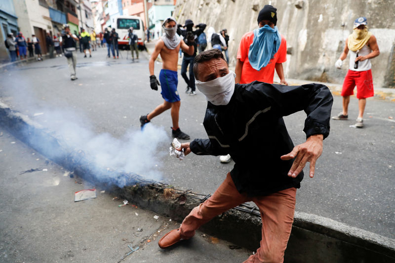 © Reuters. A demonstrator throws back a tear gas canister while clashing with Venezuelan National Guards during a protest close to one of their outposts in Caracas