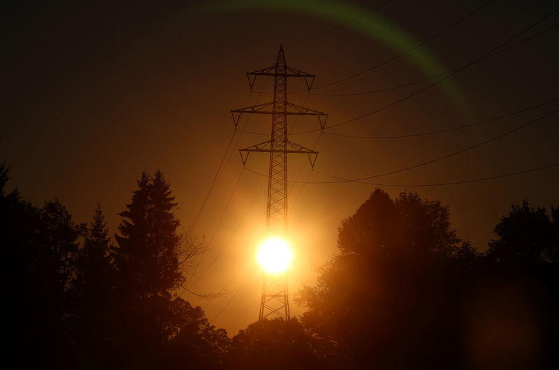 © Reuters. The sun rises behind high-voltage power lines and electricity pylons in Wall